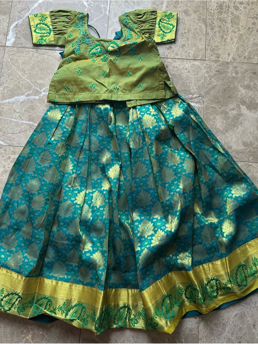 traditional pure  pattu pavadai set stands out with its intricate gold zari